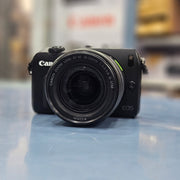 a) Canon EOS M Mirrorless Camera with 18-55mm Lens | Compact APS-C Camera (Code: AB36)