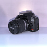 b) Canon EOS Rebel T1i DSLR Camera with 18-55mm Lens | 15.1MP | Full HD Video | Compact & Beginner Friendly | SK1032