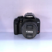b) Canon EOS Rebel T1i DSLR Camera with 18-55mm Lens | 15.1MP | Full HD Video | Compact & Beginner Friendly | SK1032